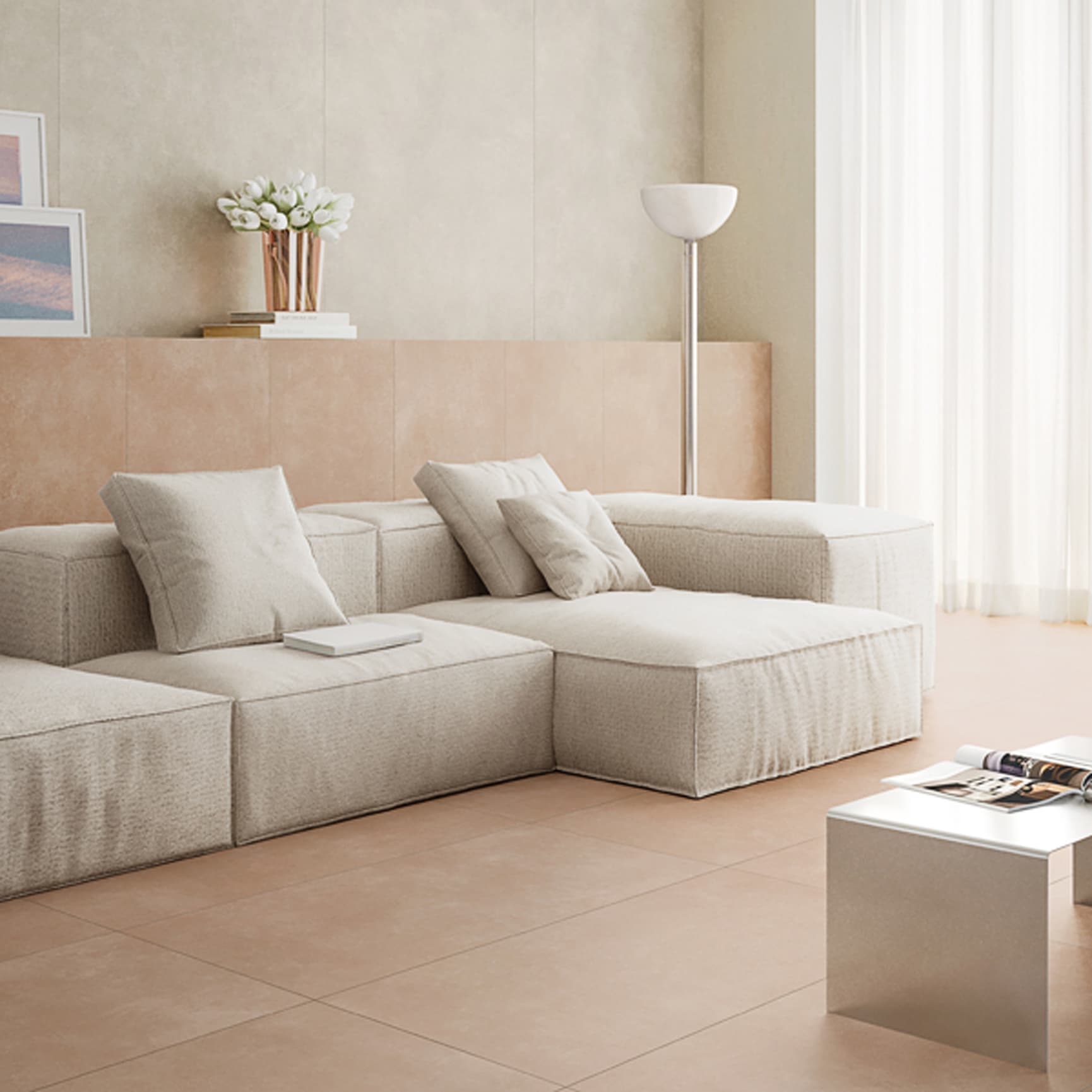 Interiørbilde av stue med lyse ferskenfargede fliser på gulv og brystning, hvit sofa og beige vegger.
